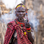 A Toposa woman exhales smoke from her Ijoo (image by Inger Vandyke)
