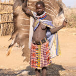 Toposa are known for hunting. Here a local woman holds a newly dried Kudu skin (image by Inger Vandyke)