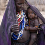With a loving gaze, the Arbore mother holds her child close. While she watches over them, the child curiously meets the camera’s eye (image by Ingrid Koedood)