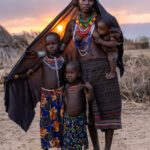 As the sun sets, its golden light filters through the shawl of this Arbore mother, embracing her and her three children in a warm glow (image by Ingrid Koedood)