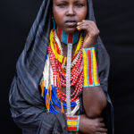 With layered necklaces and a flowing shawl, this young woman poses with the confidence of a model, embodying the beauty and pride of the Arbore people (image by Ingrid Koedood)