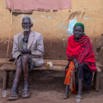 Portrait of an elderly Ari man and woman in front of a local café. The man wears his newly received reading glasses, and they suit him well (image by Ingrid Koedood)