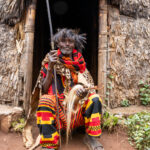 An elderly Dorze man in traditional attire, sitting in front of his home (image by Ingrid Koedood)