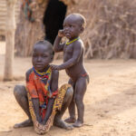 Two young Nyangatom children posing in front of a traditional house made by women (image by Ingrid Koedood)