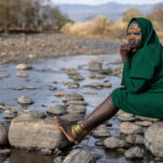 A Suri girl sits by the river’s edge, immersed in the beauty of her surroundings (image by Ingrid Koedood)