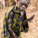 A Suri boy smears his skin with ash to protect himself from the flies (image by Ingrid Koedood)