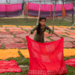 A young girl lays out newly dyed cloth to dry (image by Yousuf Tushar)