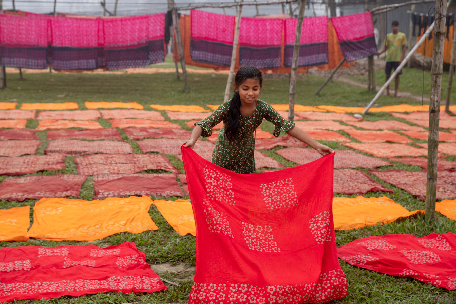 A young girl lays out newly dyed cloth to dry (image by Yousuf Tushar)