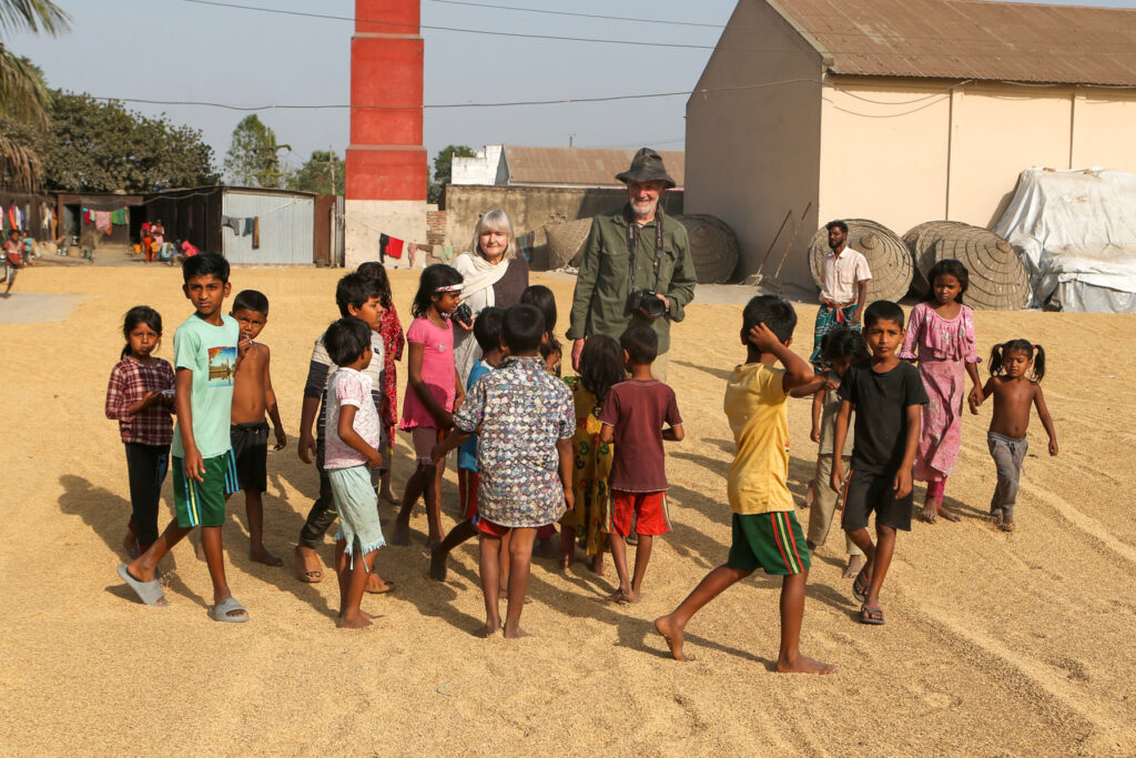 Julie and Clinton enjoying the company of the rice drying courtyard children (image by Yousuf Tushar)