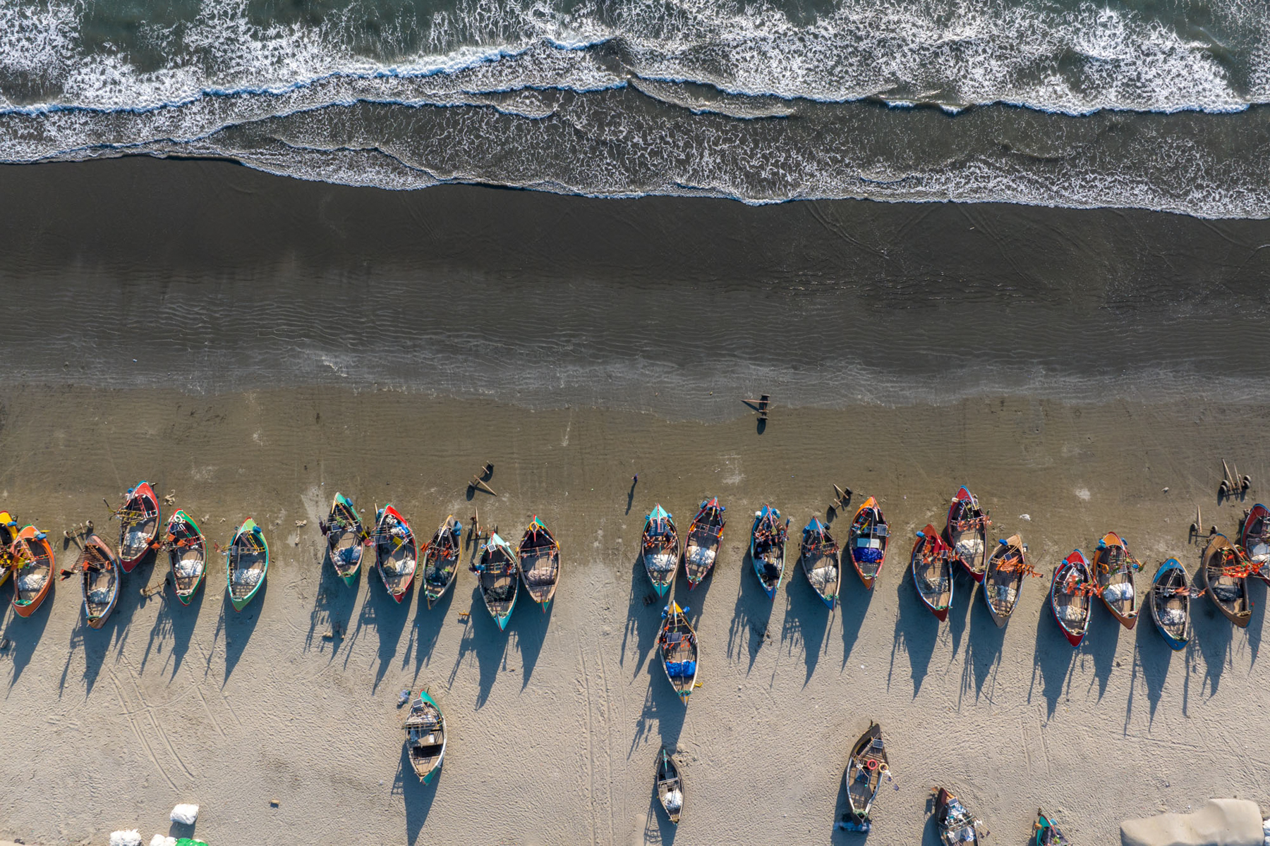 Lines of moon boats on the beach (image by Yousuf Tushar)