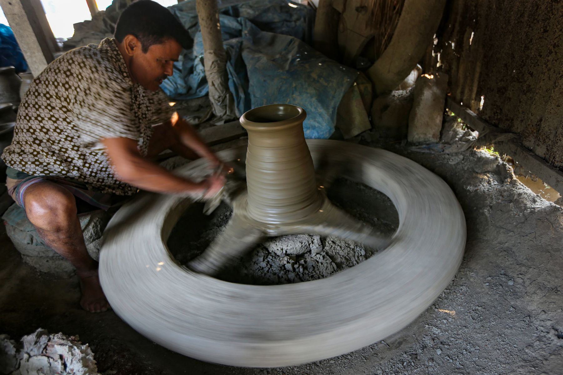 Spinning the wheel in a local pottery making facility (image by Yousuf Tushar)