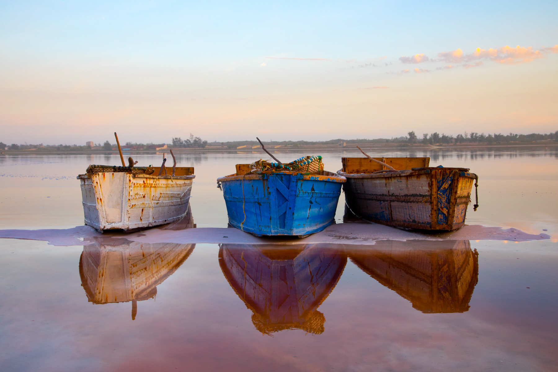 Salt boats rest on the shore of Lac Rose at sunrise. (image by Inger Vandyke)