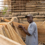 In the small fishing village of Agonvé, a fisherman patiently repair his nets, preparing for the next catch (image by Ingrid Koedood)