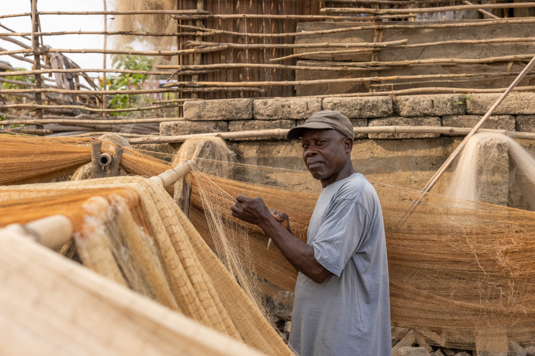 In the small fishing village of Agonvé, a fisherman patiently repair his nets, preparing for the next catch (image by Ingrid Koedood)
