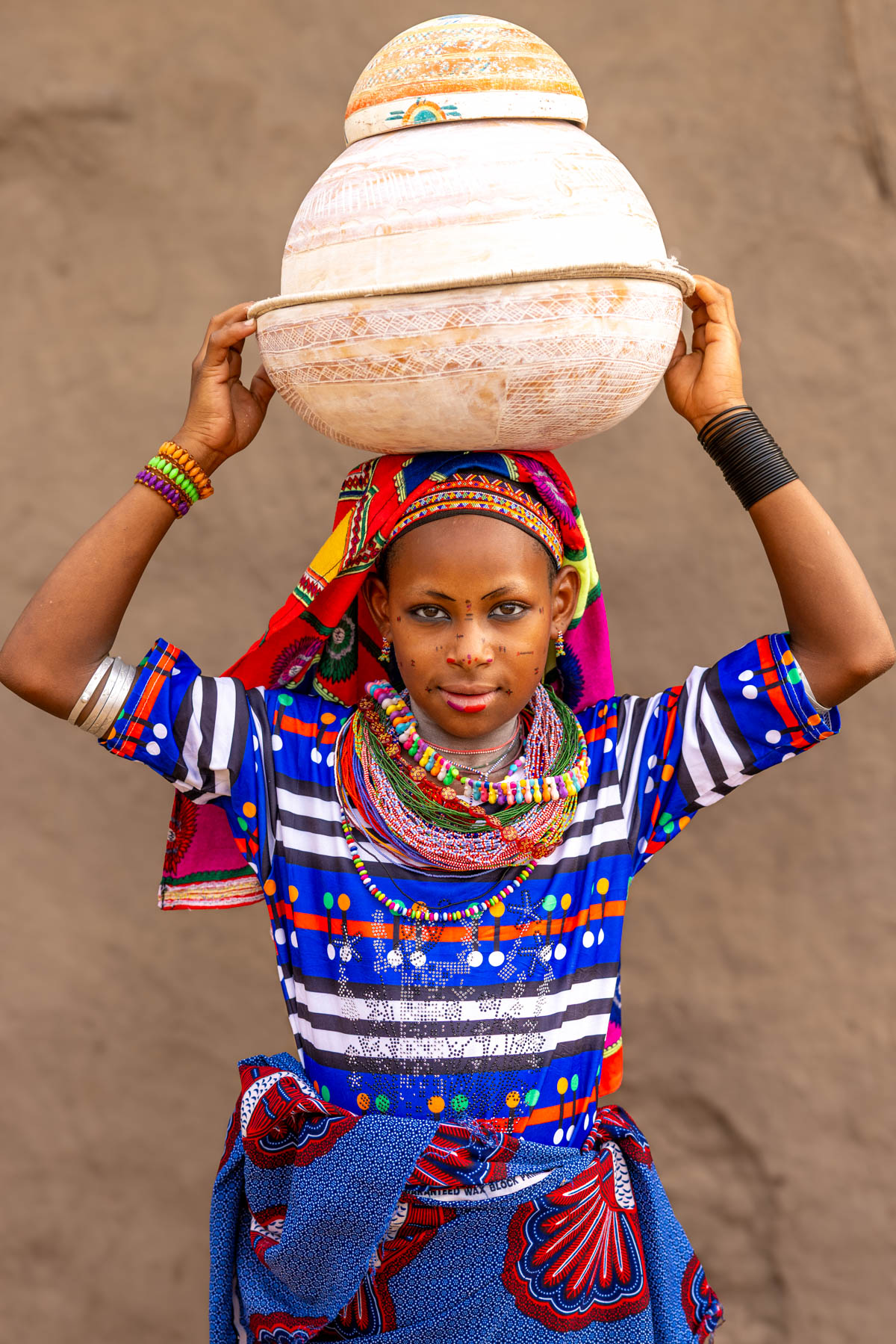 Portrait of a young Fulani woman carrying calabashes on her head (image by Ingrid Koedood)