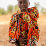A young Otamari girl with a baby on her back. Even the youngest carry big responsibilities (image by Ingrid Koedood)