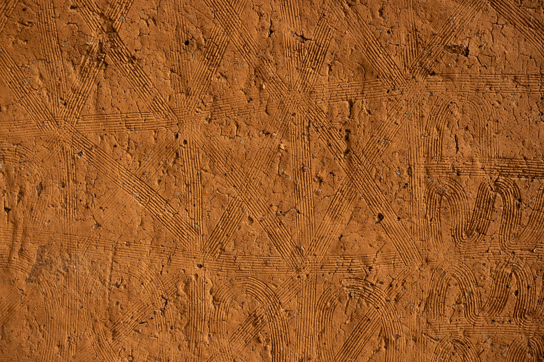 The textured wall of a tata. A UNESCO recognized earthen home, echoing the same lines of identity worn in the face by the Otamari people (image by Ingrid Koedood)