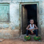 A young Zaouli dancer in the doorway of his home (image by Inger Vandyke)