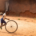 Childhood creativity: a boy playing with a bicycle tyre (image by Ingrid Koedood)