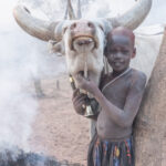 A young Dinka girl strokes her favourite cow (image by Inger Vandyke)