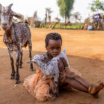 A Hamar girl with a baby goat, while the mother keeps a close eye. (image by Ingrid Koedood)
