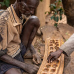 Two men playing gebeta, a traditional Ethiopean mancala game. (image by Ingrid Koedood)