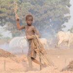 A young Mundari boy expertly readying the tethering ropes for the camp cows (image by Inger Vandyke)