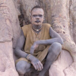 Young Mundari boy in the buttress roots of a large fig tree (image by Inger Vandyke)