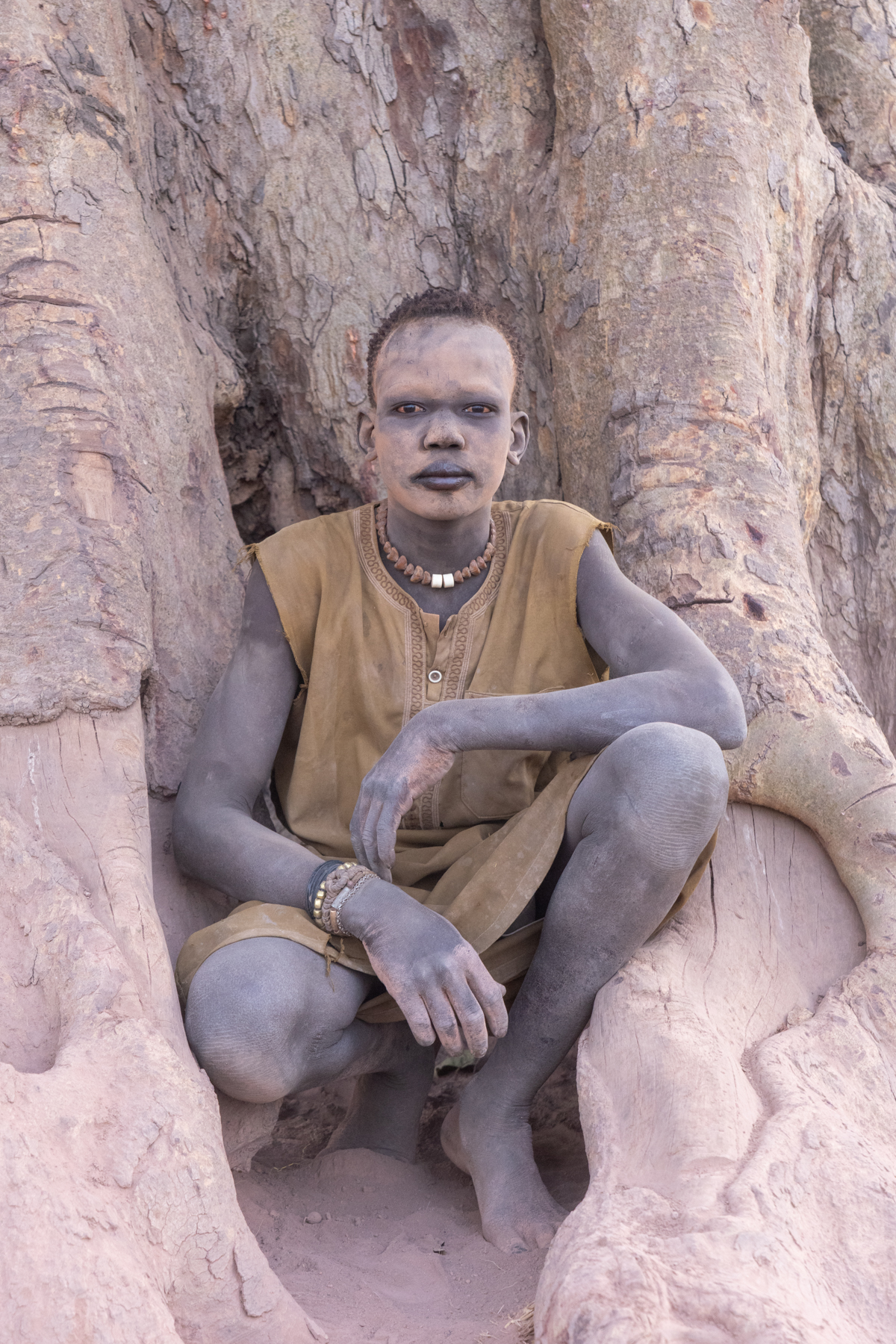 Young Mundari boy in the buttress roots of a large fig tree (image by Inger Vandyke)