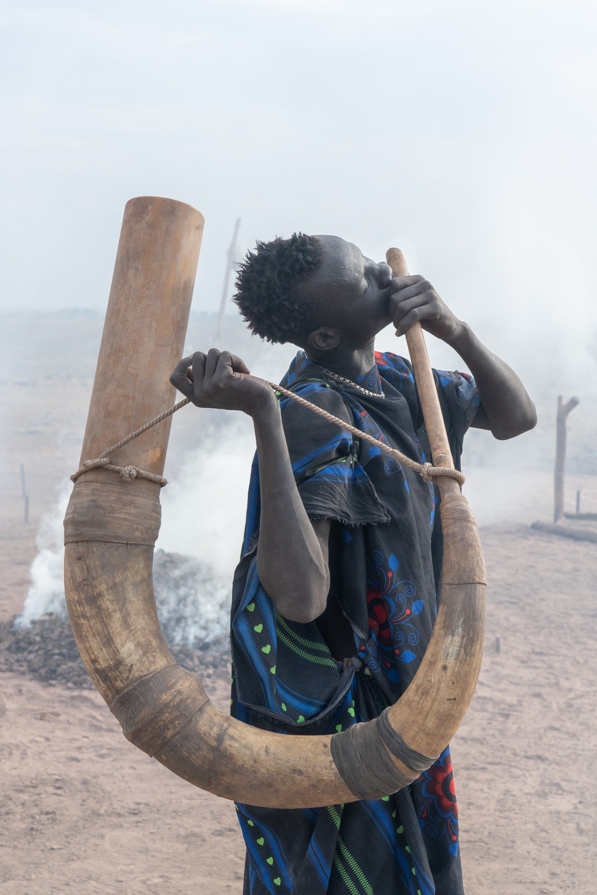 A young Mundari man playing music on a ceremonial Tung horn (image by Inger Vandyke)