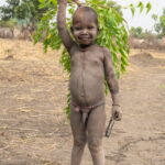 Sweet Mundari boy with a tree branch which will be used as the camp broom (image by Inger Vandyke)
