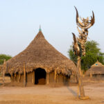 A traditional Mundari home with the marked gravesite of an elder (image by Inger Vandyke)