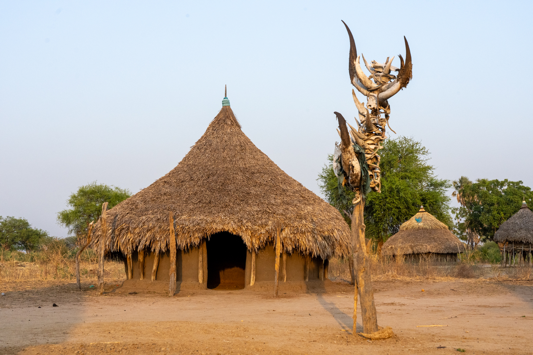 A traditional Mundari home with the marked gravesite of an elder (image by Inger Vandyke)