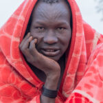 Early morning Mundari man draped in a blanket to stay warm (image by Inger Vandyke)