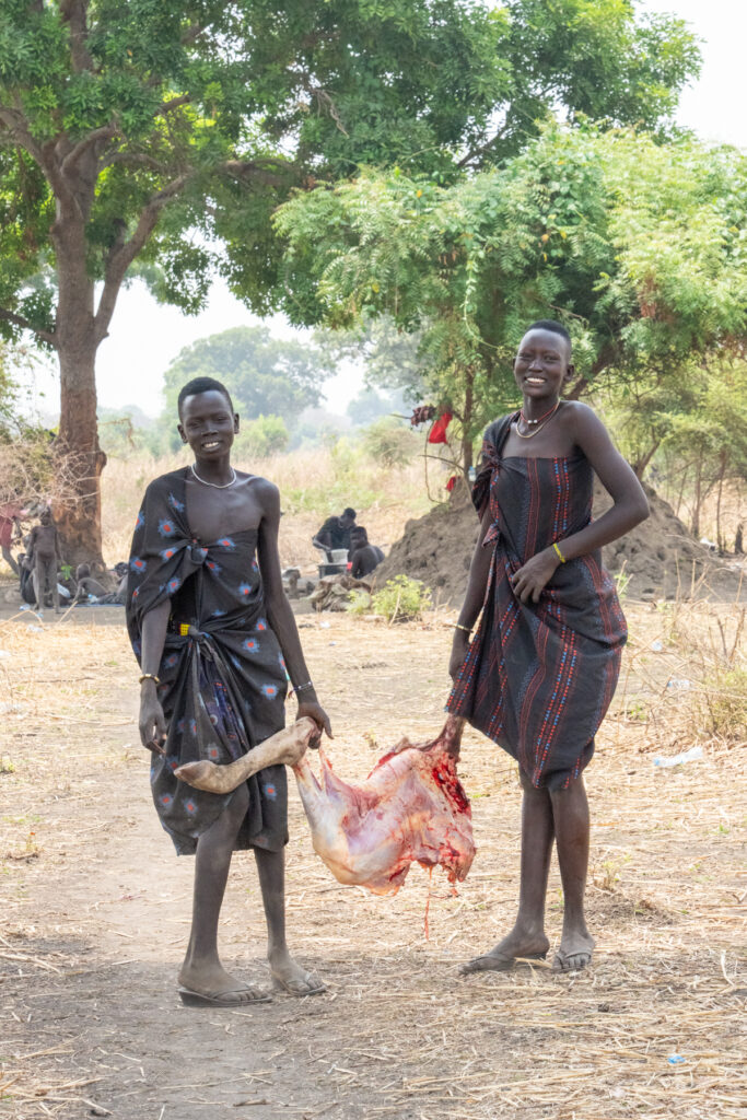 Mundari women carrying the carcass of the dead calf to make stew (image by Inger Vandyke)