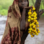 A Mursi girl watching from a distance as we photograph, while the rain slowly sets in. (image by Ingrid Koedood)