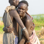 Young Mundari men embrace after wrestling practice (image by Inger Vandyke)