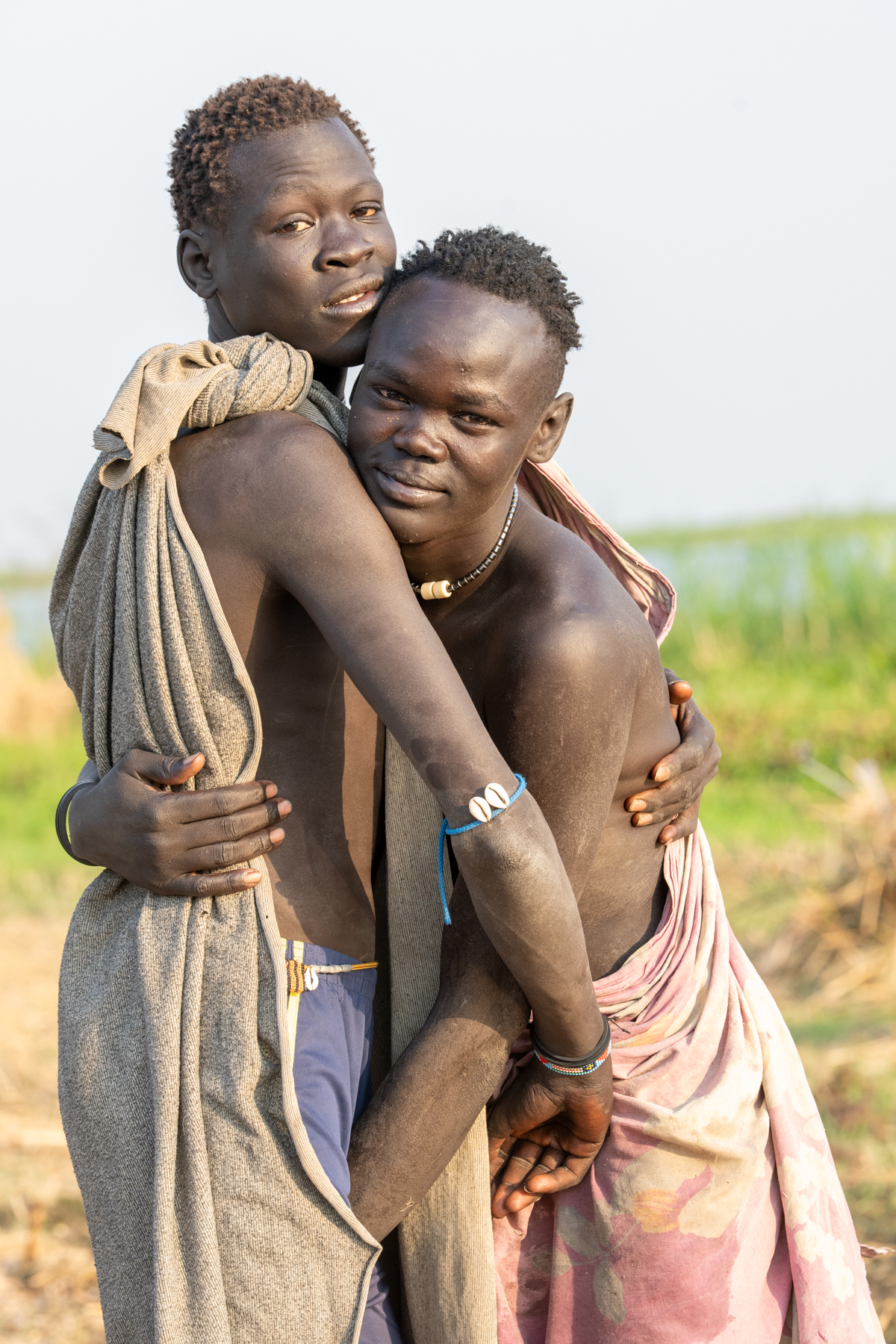 Young Mundari men embrace after wrestling practice (image by Inger Vandyke)