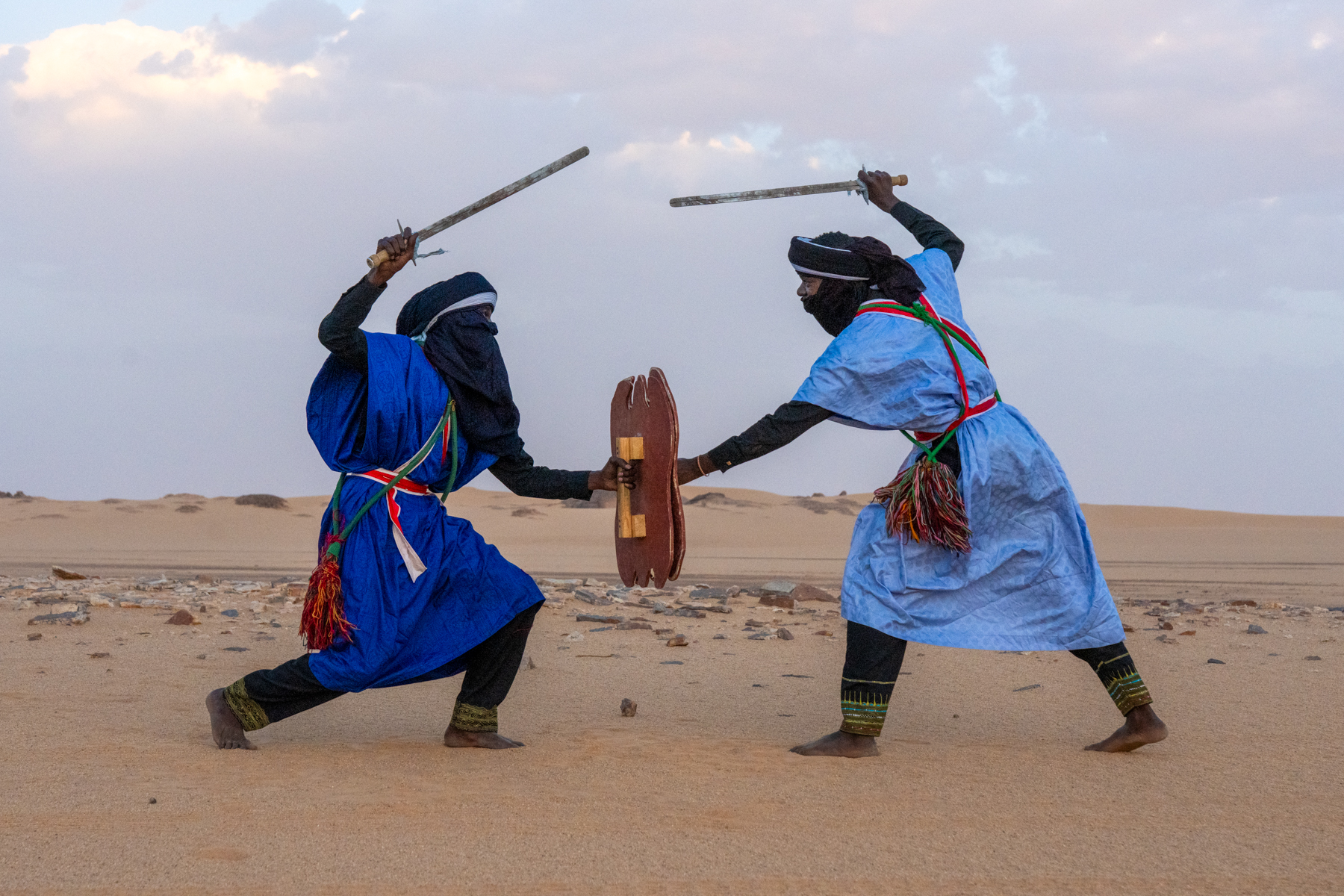 Aroukas warriors engage in a mock sword battle at sunset in the desert (image by Inger Vandyke)