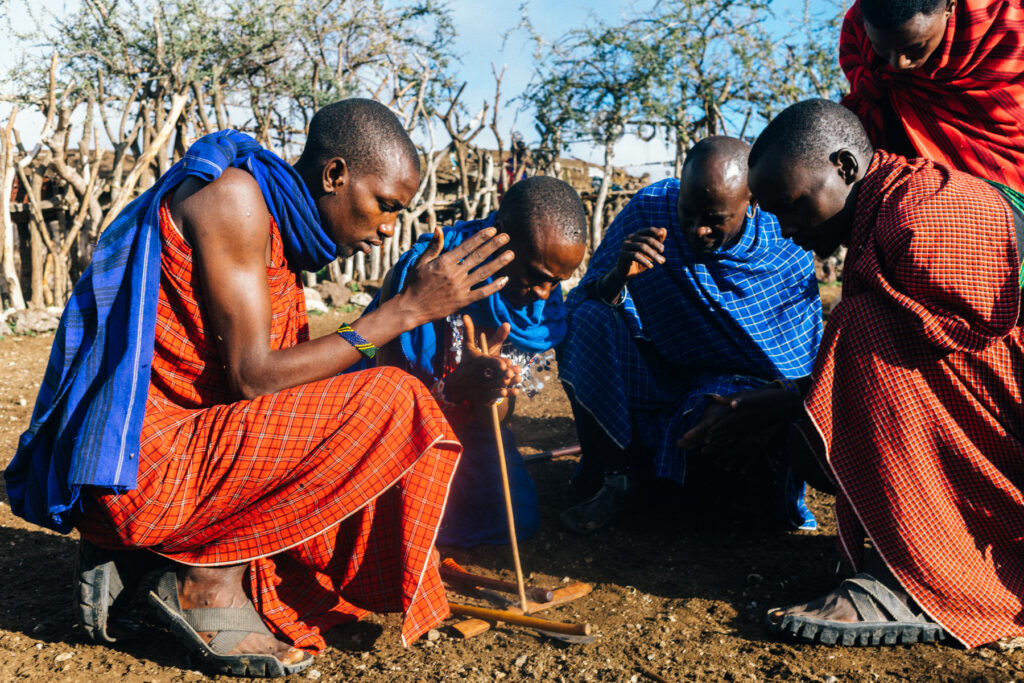 Maasai men demonstrate the traditional art of making fire outside their boma - a fenced, family homestead where people and livestock live side by side (image by Virginia Wilde)