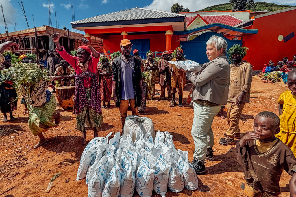 Tour member Ann helps to hand a month's worth of food to members of the displaced Echuya Twa community in Uganda (image by Virginia Wilde)