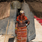 A Rendille woman wearing her Mbaro necklace at the entrance of a local spirit house (image by Inger Vandyke)