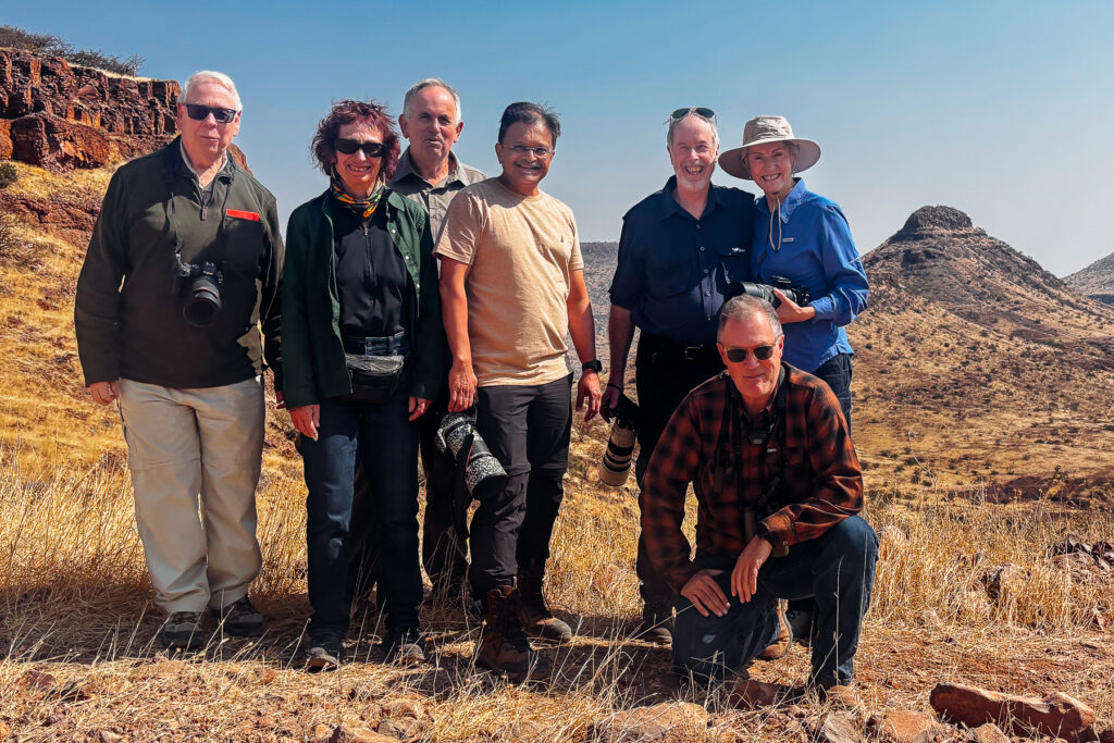 Our brilliant Namibia 2026 tour members pose with co-leader Mike Watson during a break from our road trip towards Namibia's Hoanib River Valley (image by Virginia Wilde)
