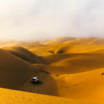 One of our 4x4 vehicles sweeps over dunes during an adventure drive day to Namibia's Sandwich Harbour, part of the Namib-Naukluft National Park. Some of the dunes rise to more than 100 metres in places, before running directly down towards the Atlantic Ocean (image by Virginia Wilde)
