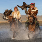 Bashakan and his son, Serekjan, ride through the water with their golden eagles (image by Ingrid Koedood)
