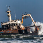 The wreck of the Zelia lies stranded on Namibia's Skeleton Coast, its rusting hull battered by the Atlantic surf. Hundreds of Cape cormorants have claimed the remains of the vessel as a perch, covering its masts and hull (image by Virginia Wilde)