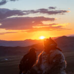 After a cold night in the mountains, the first rays of the rising sun bring warmth to the eagle hunter and his golden eagle (image by Ingrid Koedood)